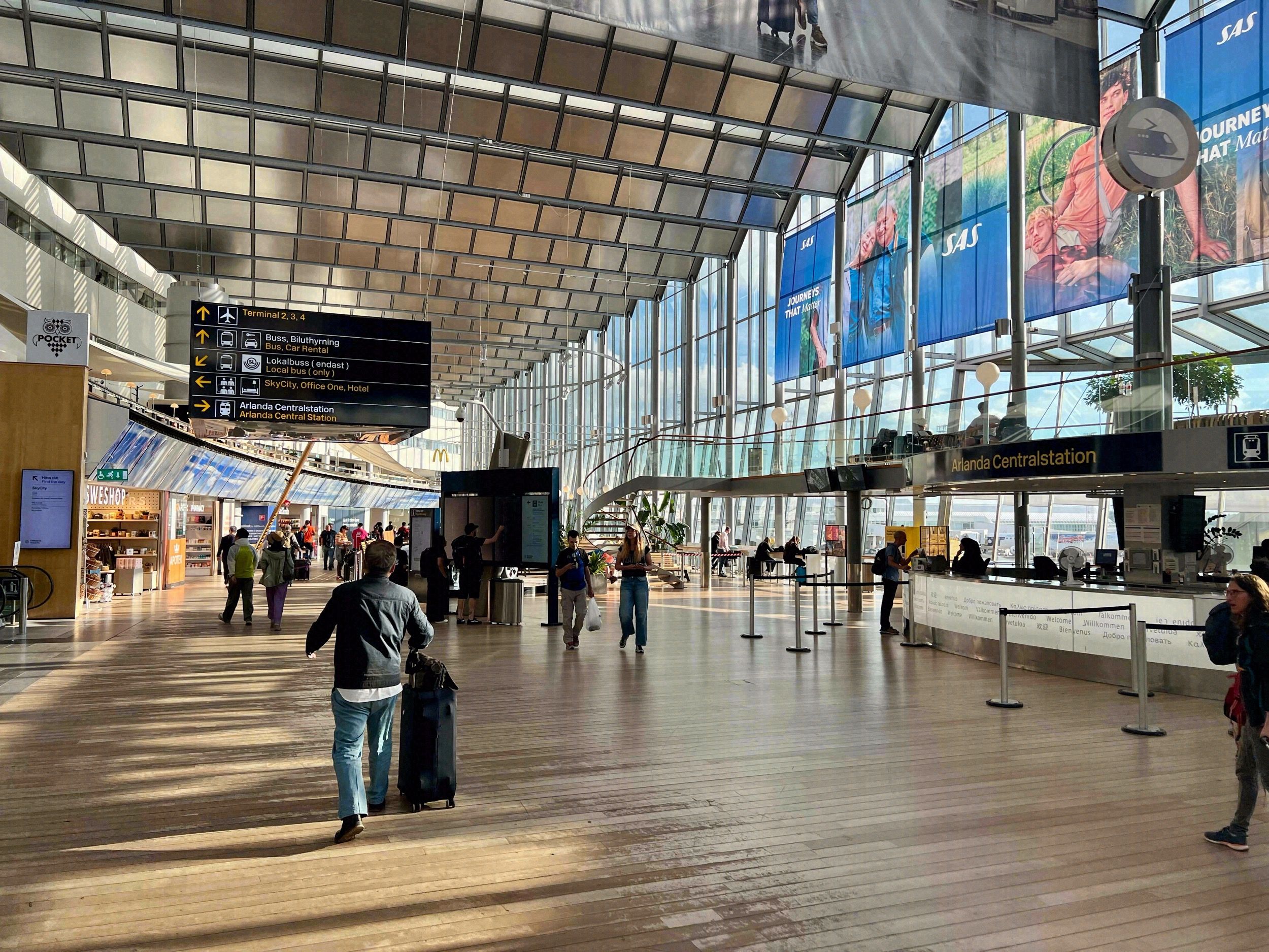 Abflughalle des Flughafens Stockholm-Arlanda mit SAS-Werbung und Wegweisern zur Arlanda Centralstation.