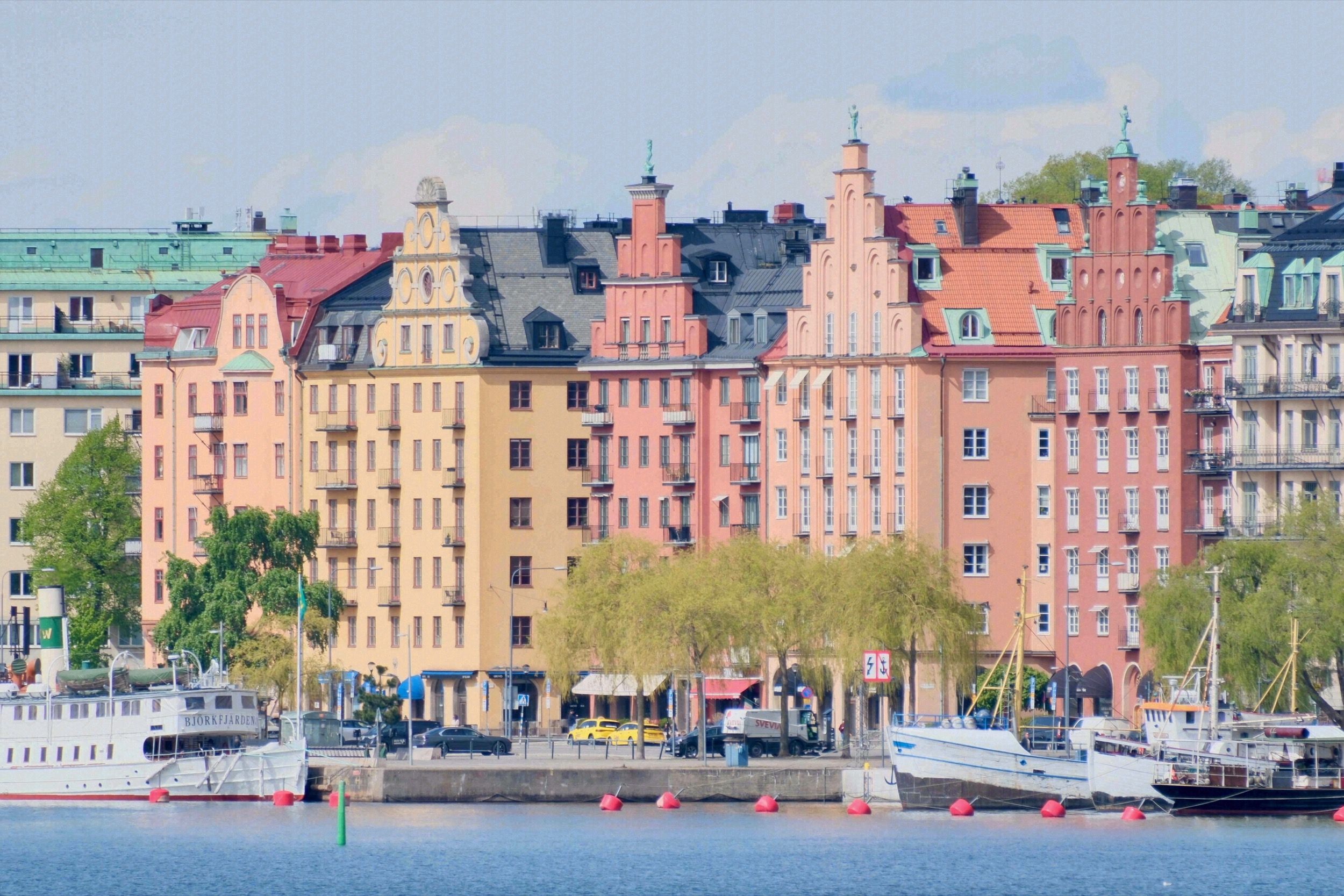 Bunte historische Fassaden der Kungsholmen-Uferfront vom Wasser aus gesehen, mit Booten im Vordergrund.