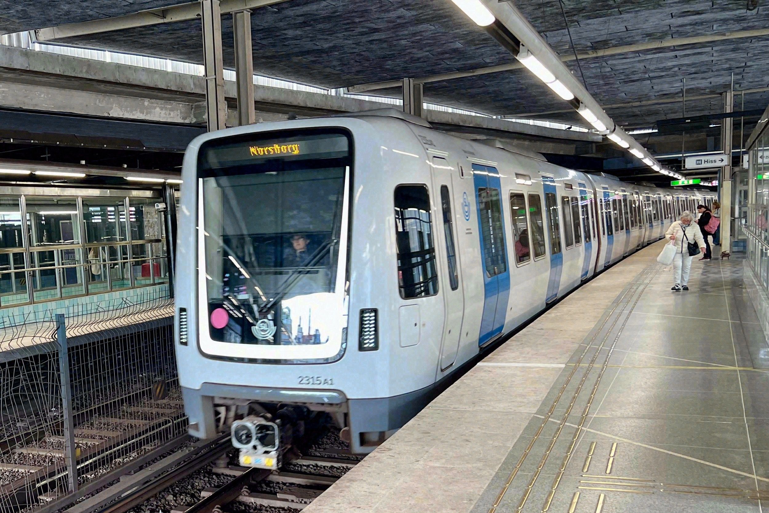 Stockholmer Tunnelbana-Zug (Richtung Norsborg) fährt in eine oberirdische U-Bahn-Station ein.