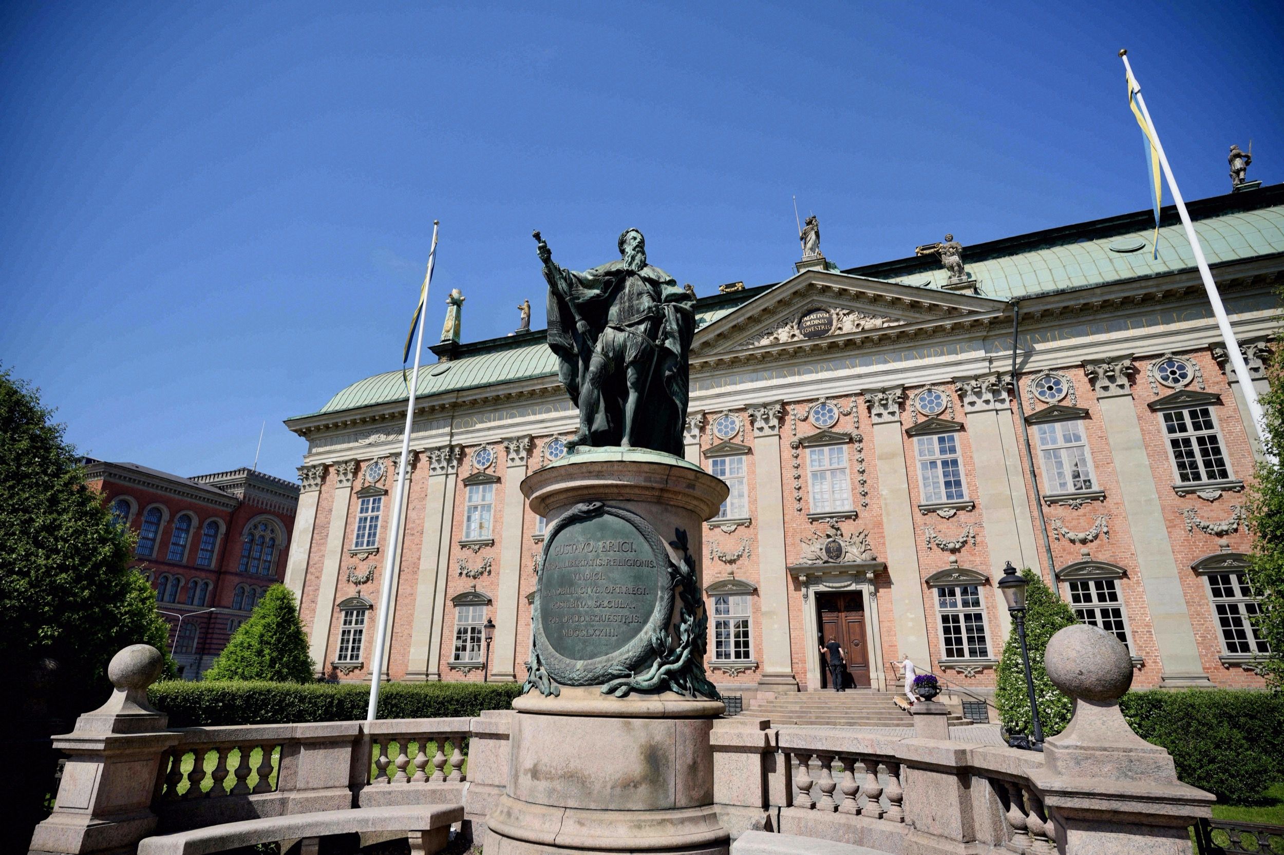 Fassade des Riddarhuset (Adelshaus) mit der Reiterstatue auf dem Vorplatz und schwedischen Flaggen.