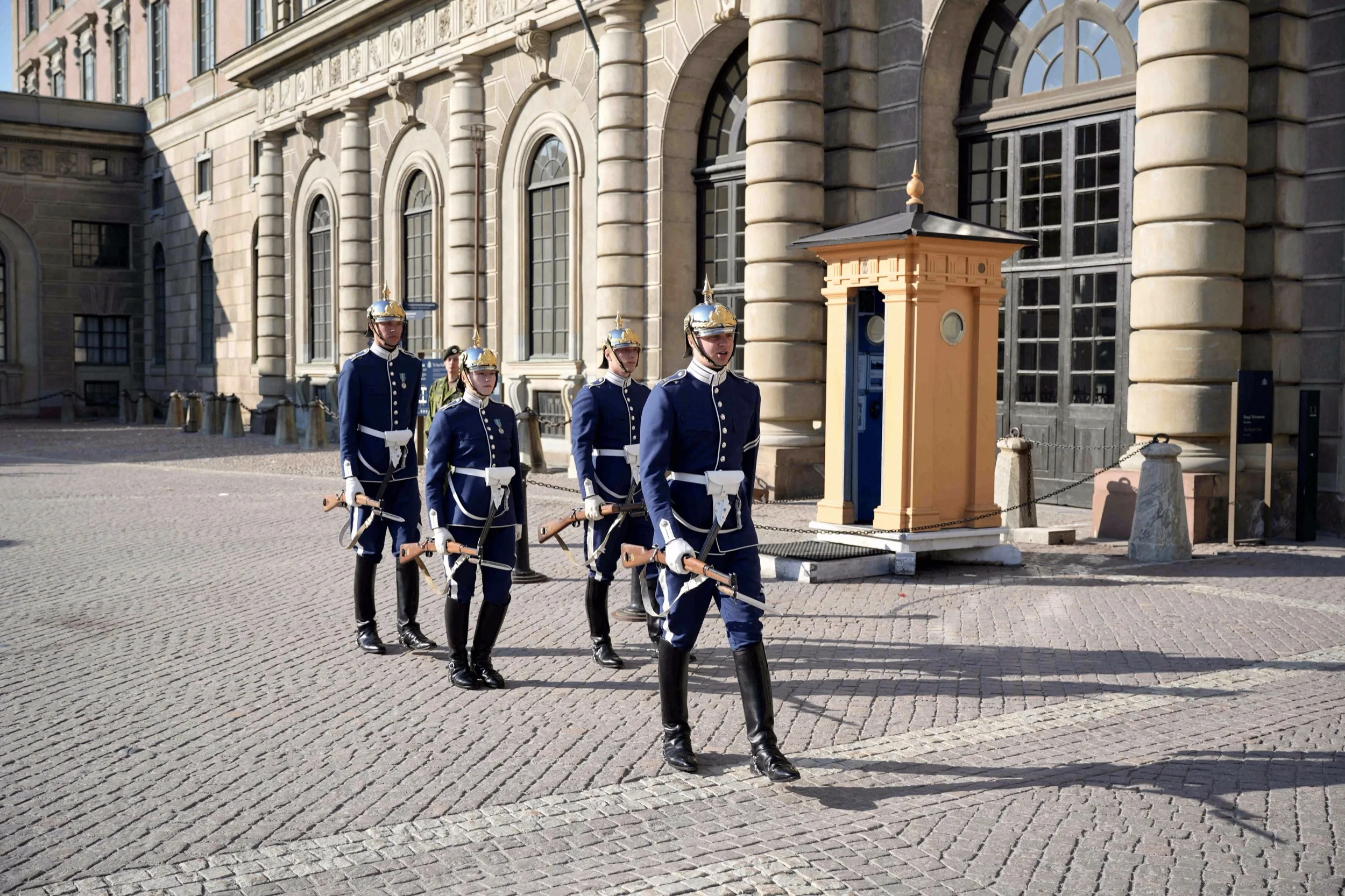 Vier Soldaten in blauer Galauniform marschieren bei der Wachablösung über den Schlosshof