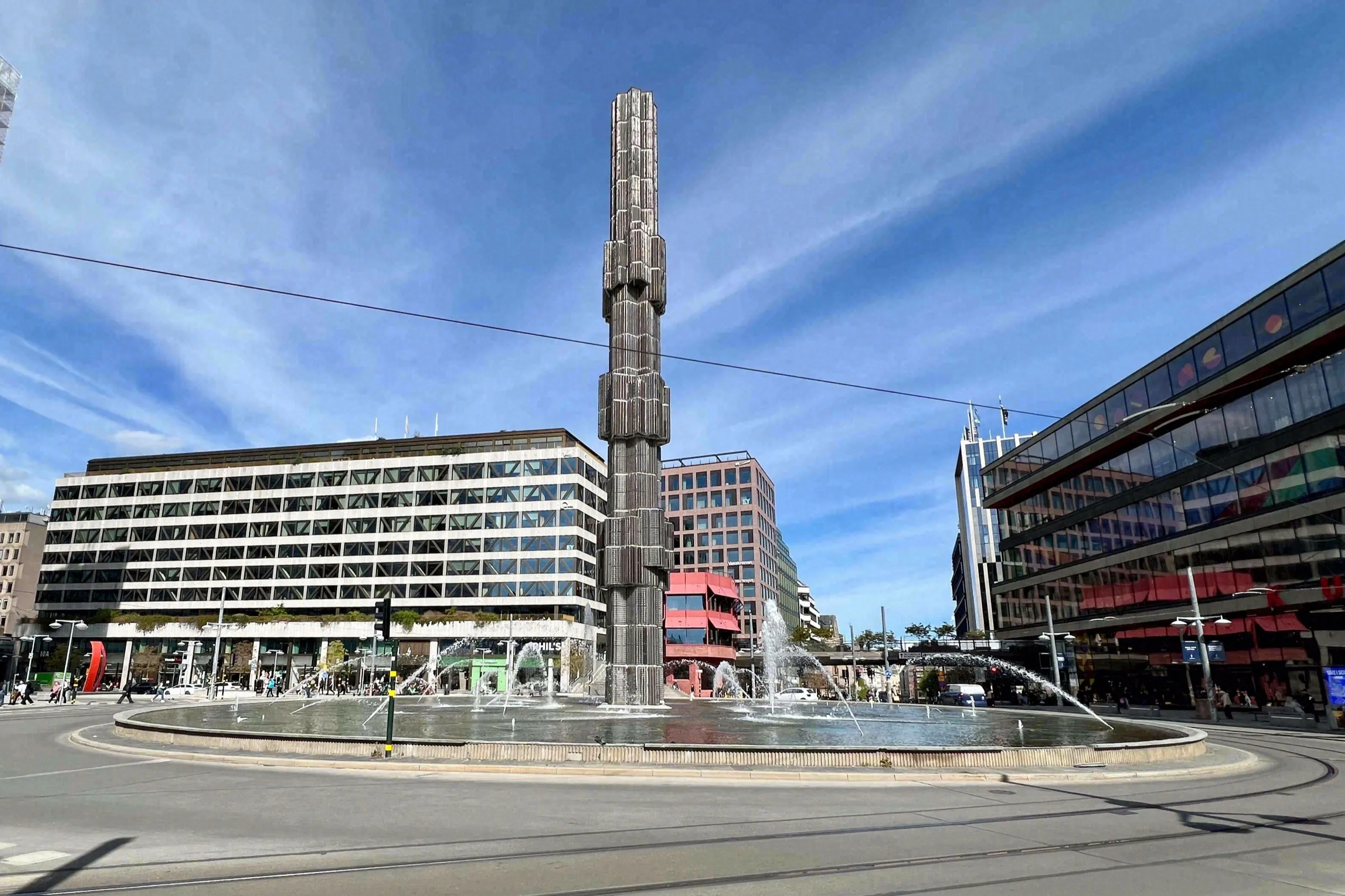 Sergels torg mit der hohen Glassäule und der Fontäne inmitten der Stadtbebauung
