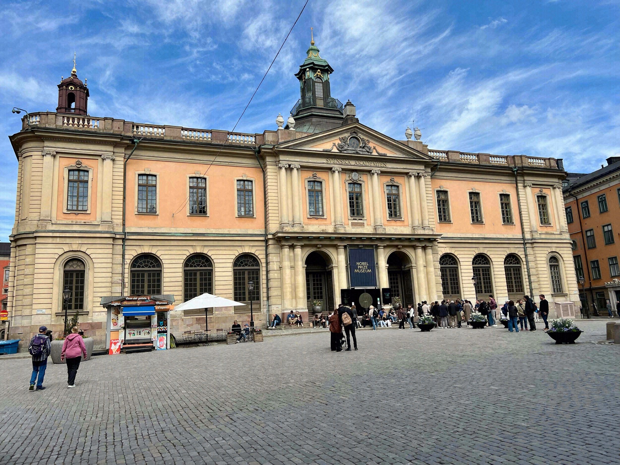 Fassade des Nobel Prize Museum am Stortorget in Gamla Stan mit dem markanten orangefarbenen Barockbau der Börse.