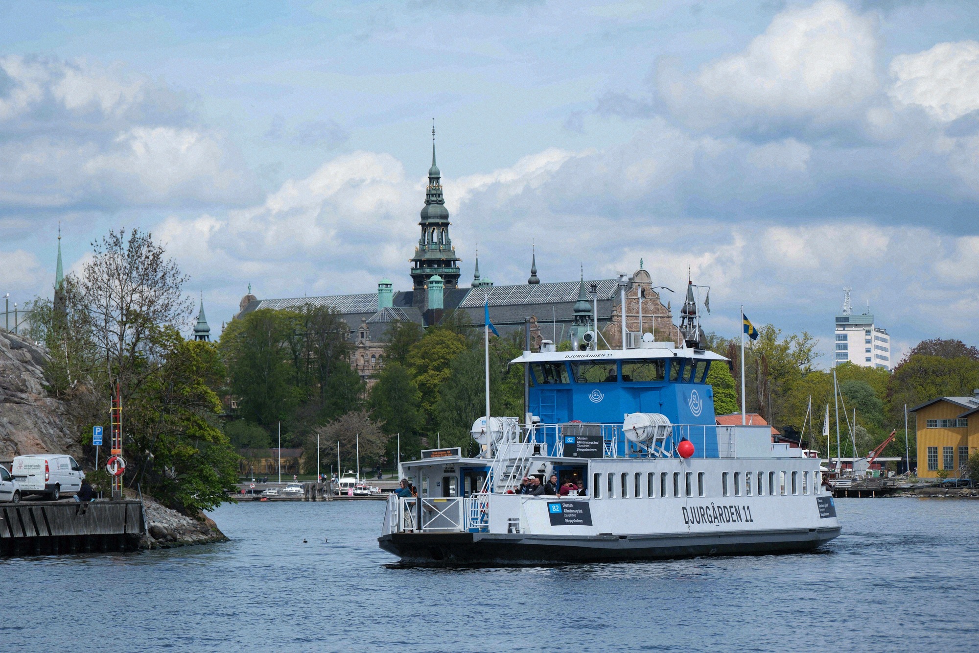 The Djurgården ferry 11 passes in front of the Nordiska museet on Djurgården, its distinctive tower visible in the background.