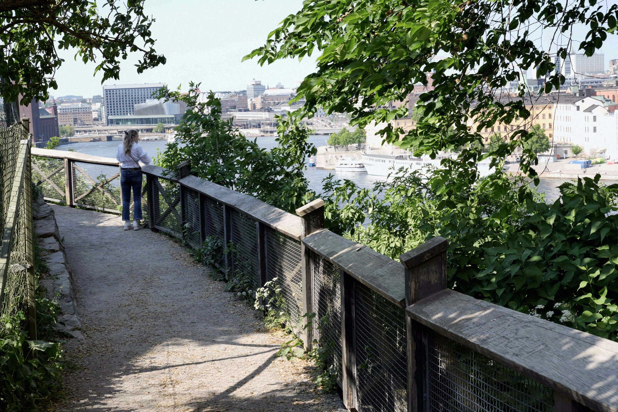 The Monteliusvägen viewpoint path, with a view across the water to the city centre. Woman walking the Monteliusvägen viewpoint path with a view across the water to the city centre