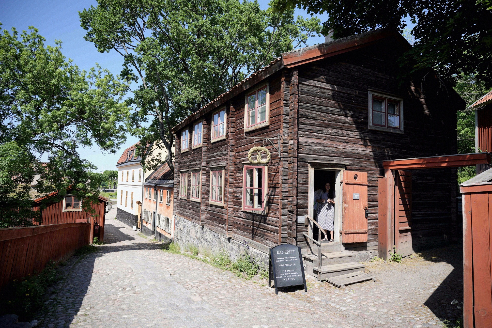 Historic wooden houses at the open-air museum, including the Rageriet print shop. Historic wooden houses on a cobbled lane at the Skansen open-air museum