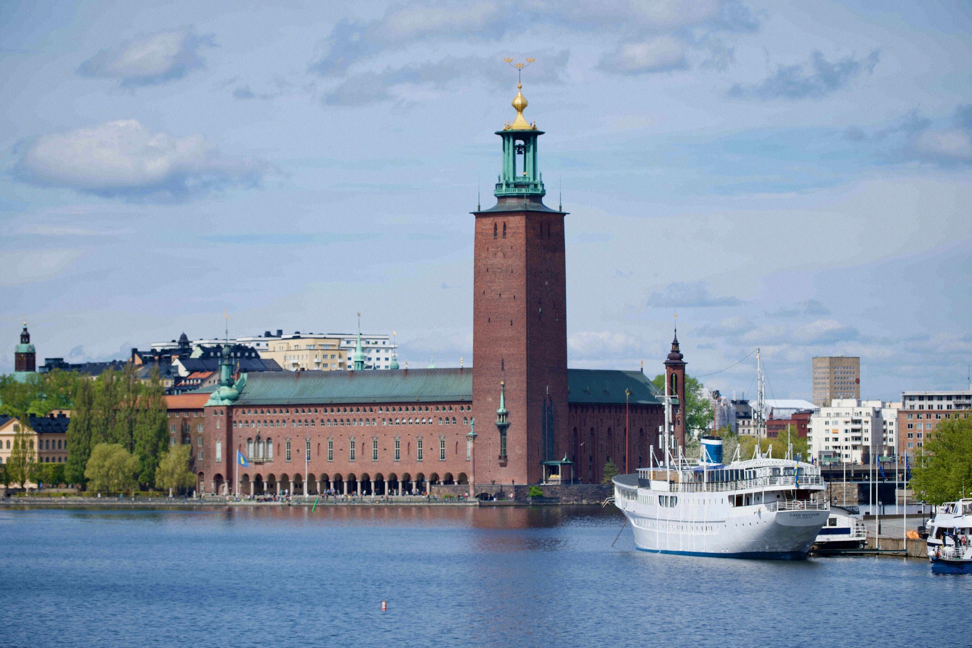 Stockholm City Hall with its distinctive brick tower and golden crown, seen from the water