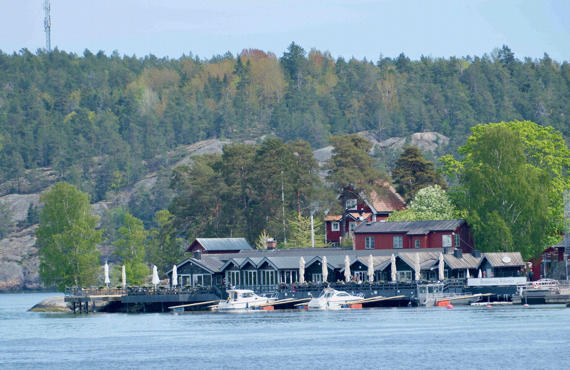 Ein Restaurant mit Steg und Bootsliegeplätzen an einer bewaldeten Schäreninsel im Stockholmer Archipel.