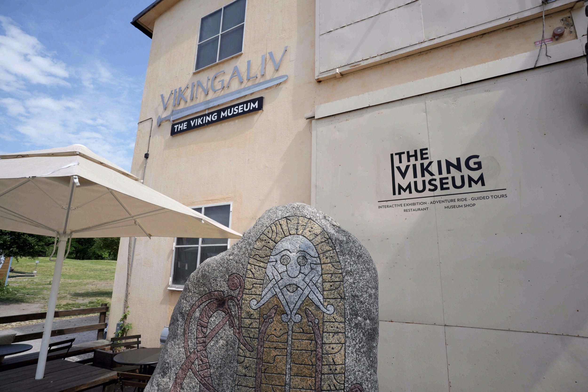 Exterior facade of the Vikingaliv Viking Museum on Djurgården, with a rune stone sculpture in front of the entrance.